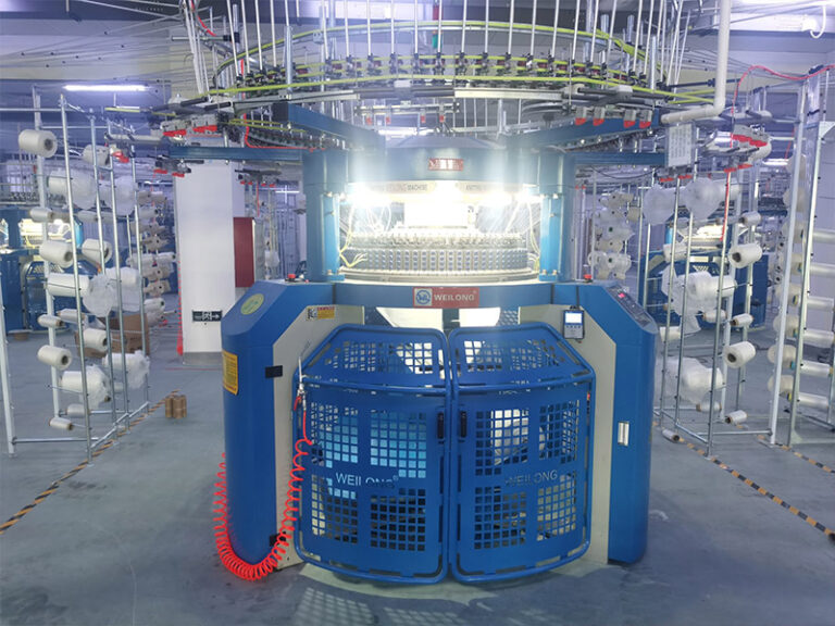 Large circular knitting machine with yarn cones in a workshop